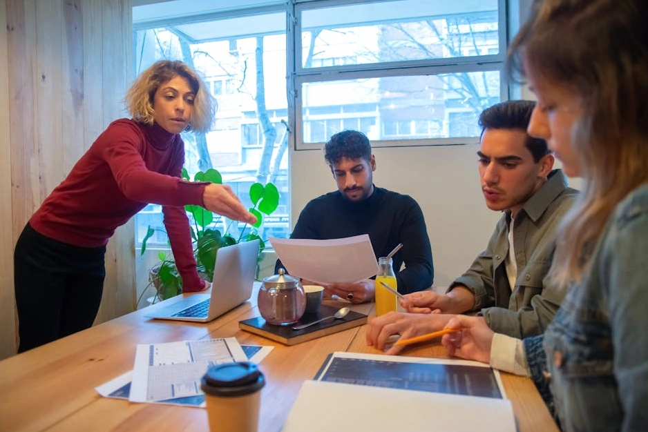 A team of professionals in a workshop discussing strategy around a table with notes.